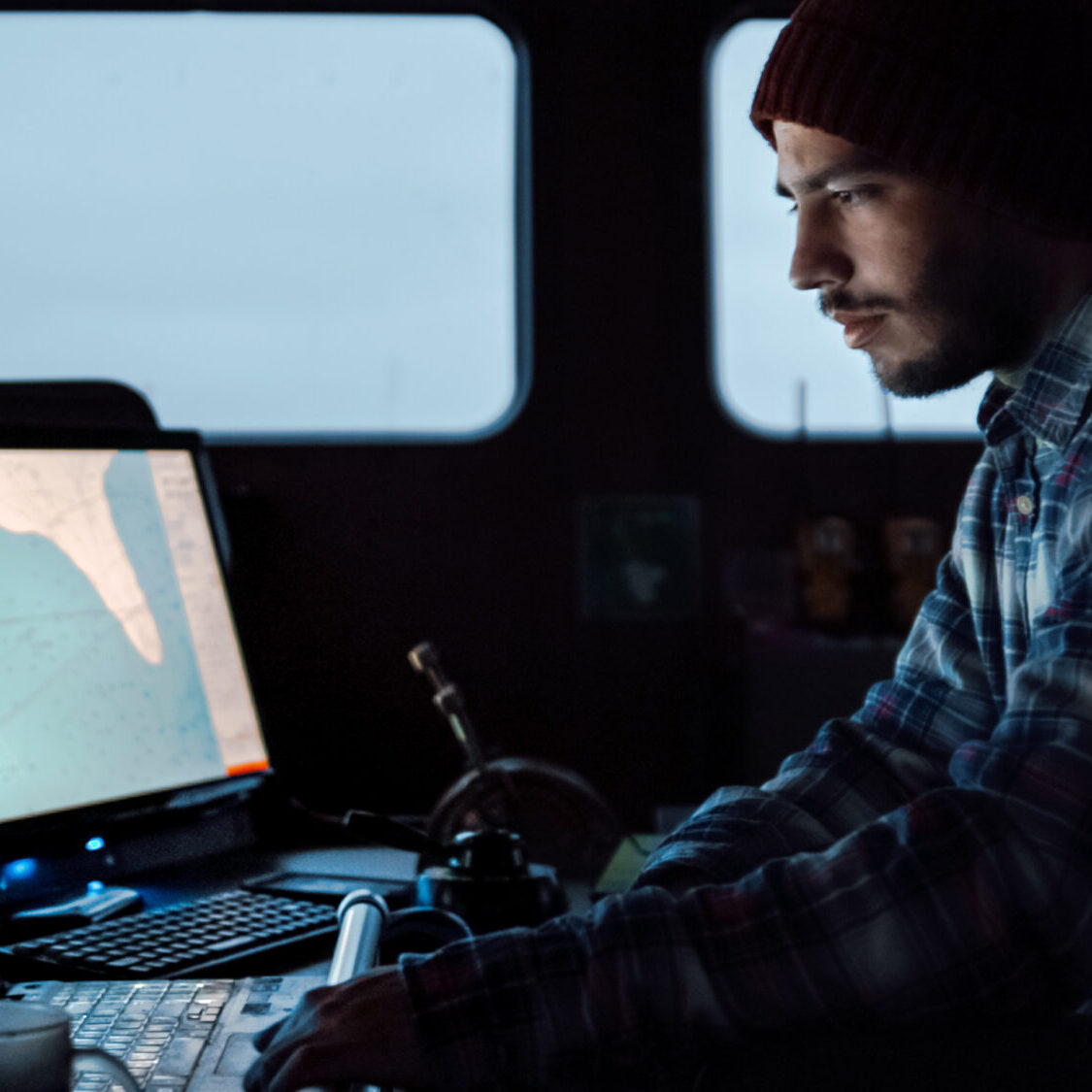 Shot of a Serious Captain on a Commercial Fishing Ship Surrounded by Monitors and Screens Working with Sea Maps Pilots.